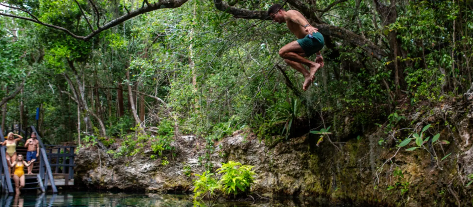 Turista saltando a una laguna natural en la Reserva Ojos Indígenas, Punta Cana