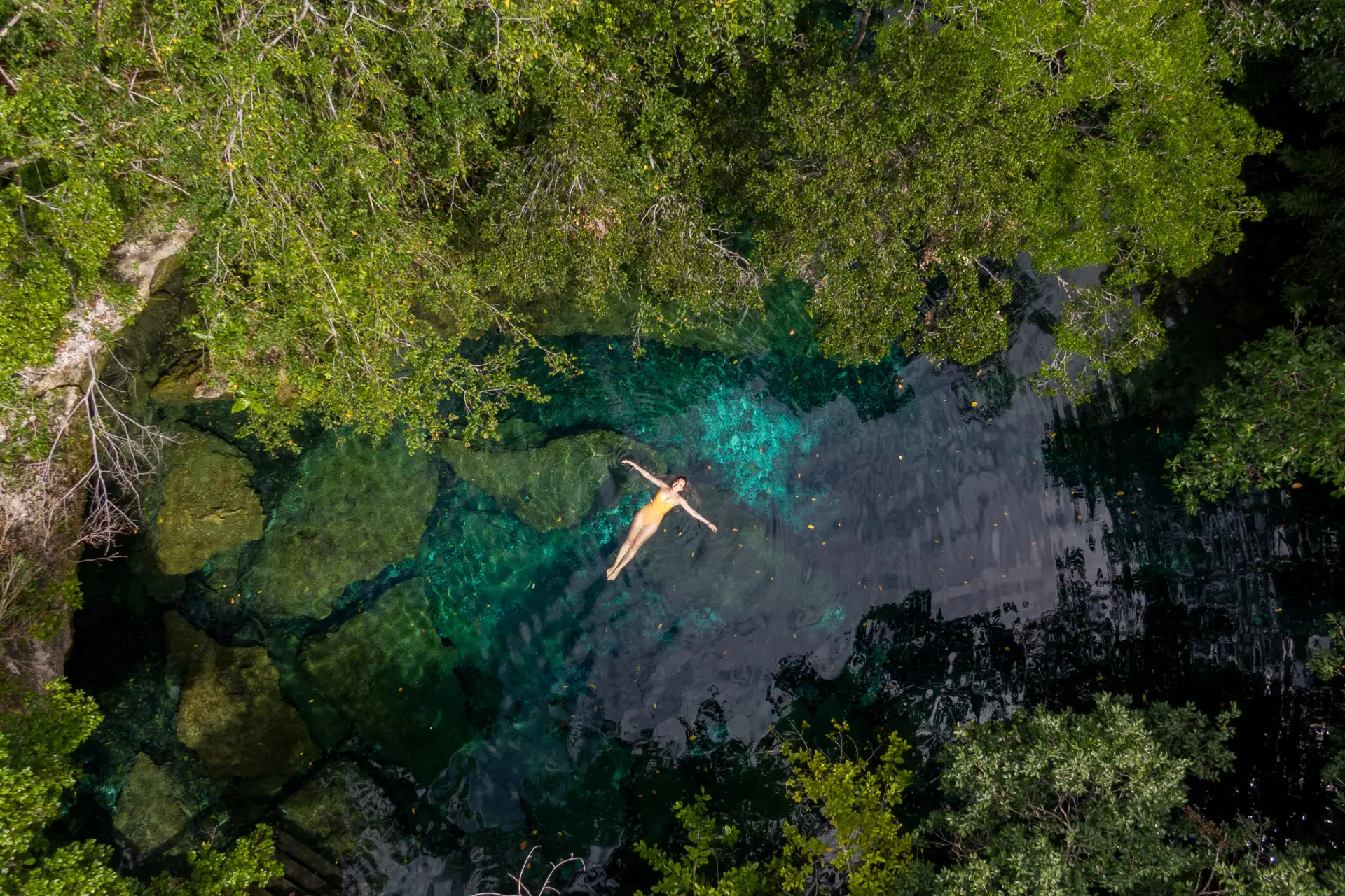 Vista aérea de mujer flotando en laguna cristalina de la Reserva Ojos Indígenas, Punta Cana