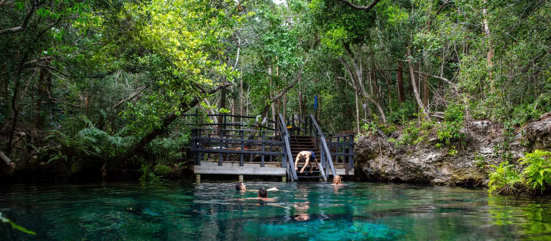 Turistas nadando y saltando en laguna cristalina de Ojos Indígenas