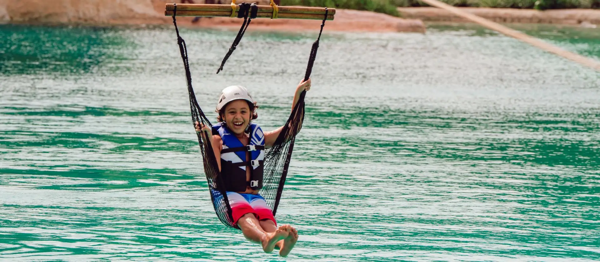 Parque aventura Cap Cana: niño en tirolesa sobre laguna de agua cristalina