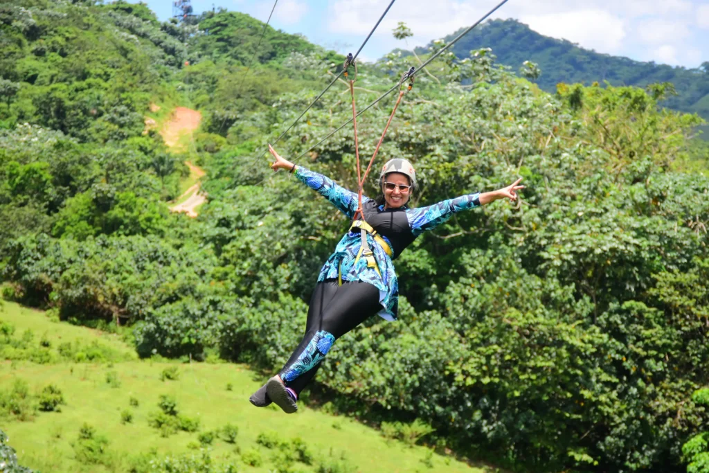 Mujer disfrutando de la tirolesa con los brazos abiertos en La Hacienda Park