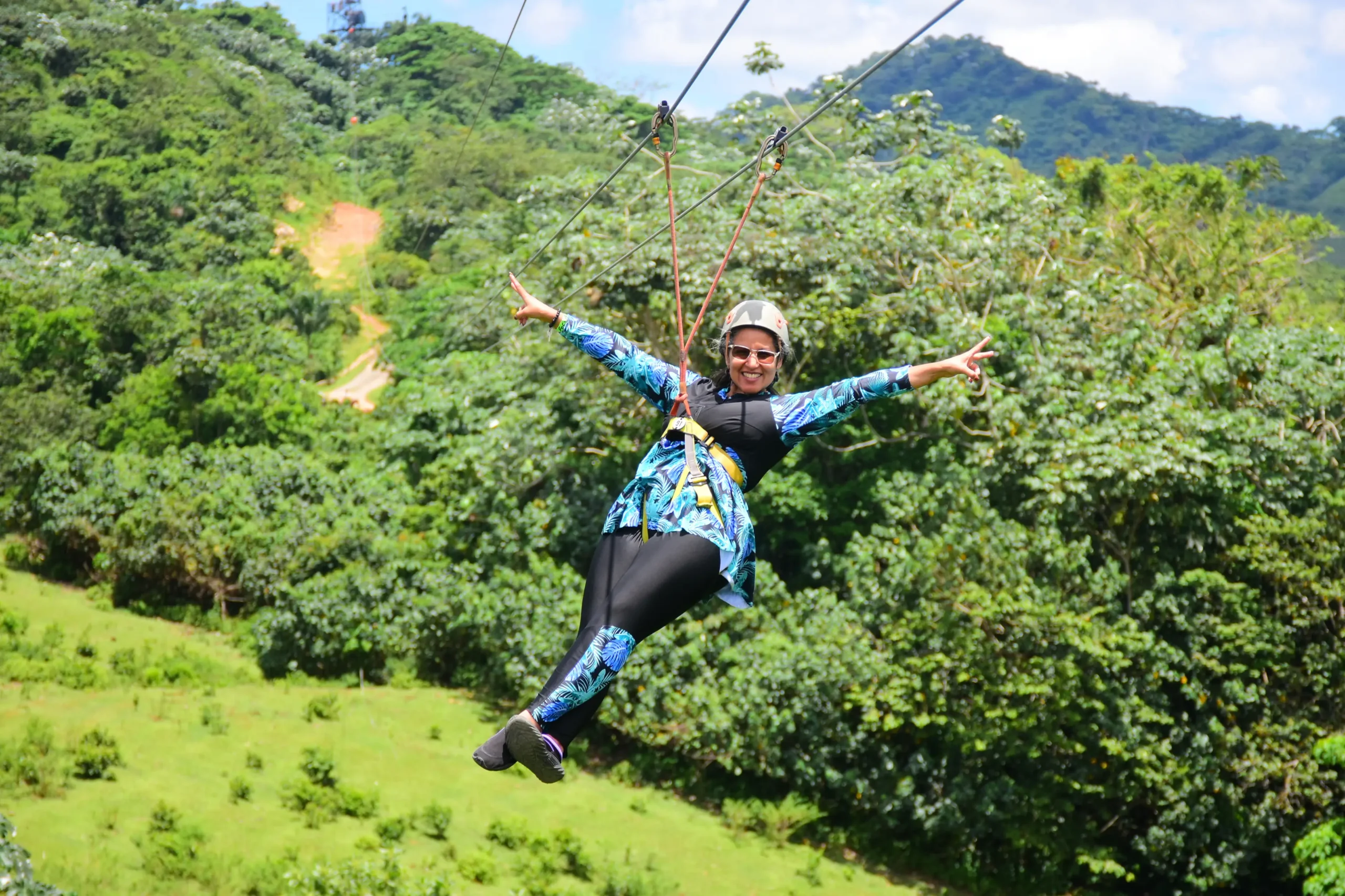 Mujer disfrutando de la tirolesa con los brazos abiertos en La Hacienda Park